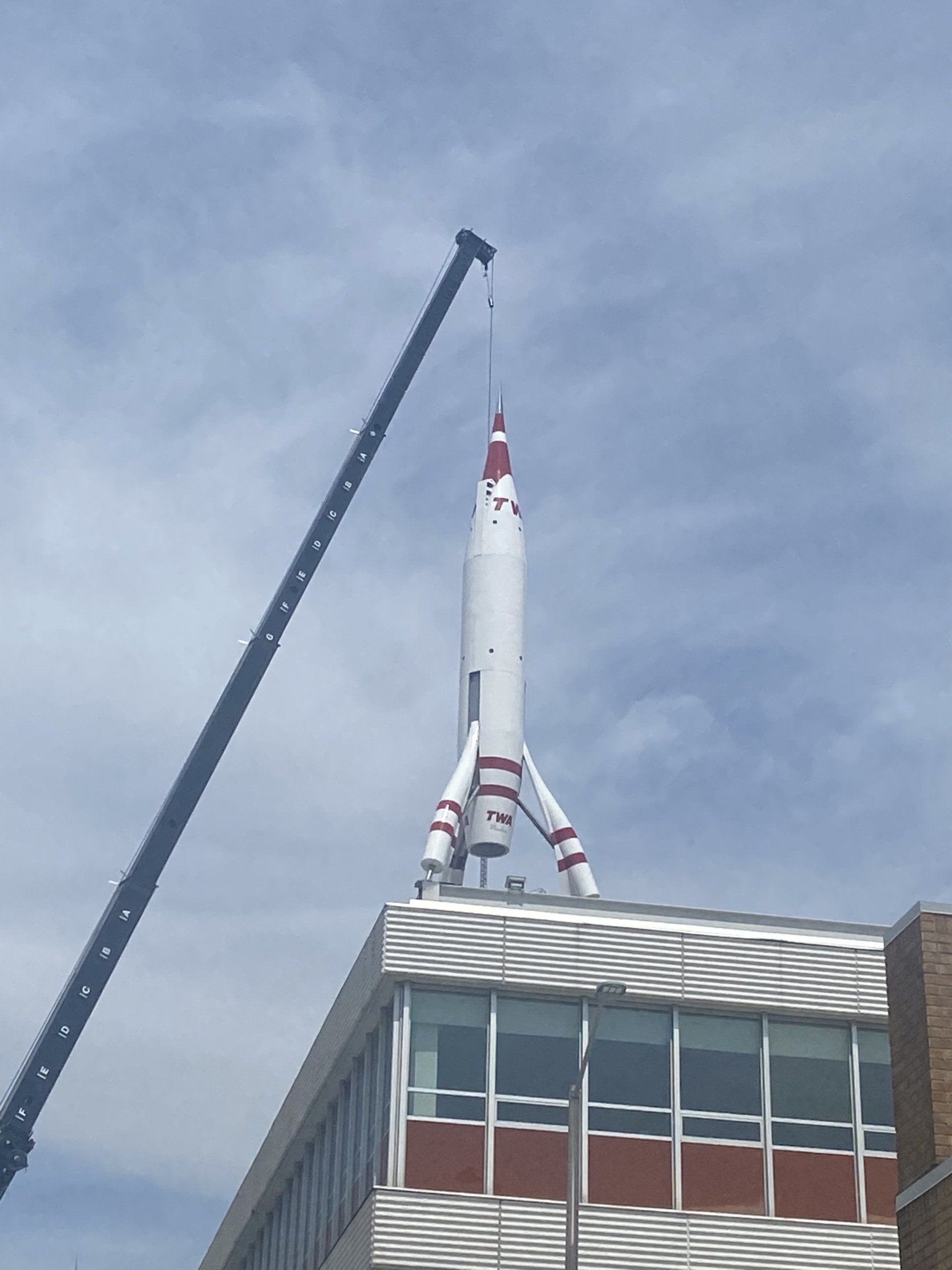 A crane is lifting a rocket on top of a building