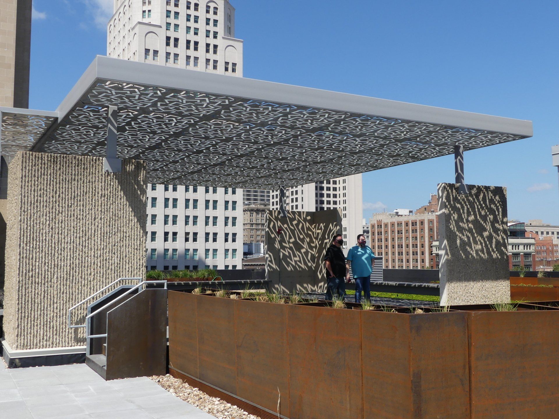 Two men standing under a canopy in front of a building