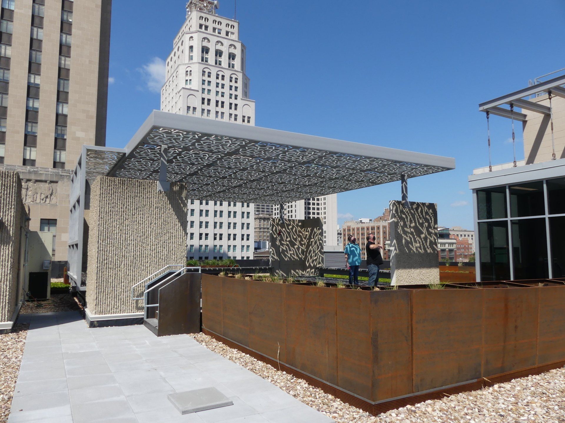 Two people standing under a canopy on the roof of a building