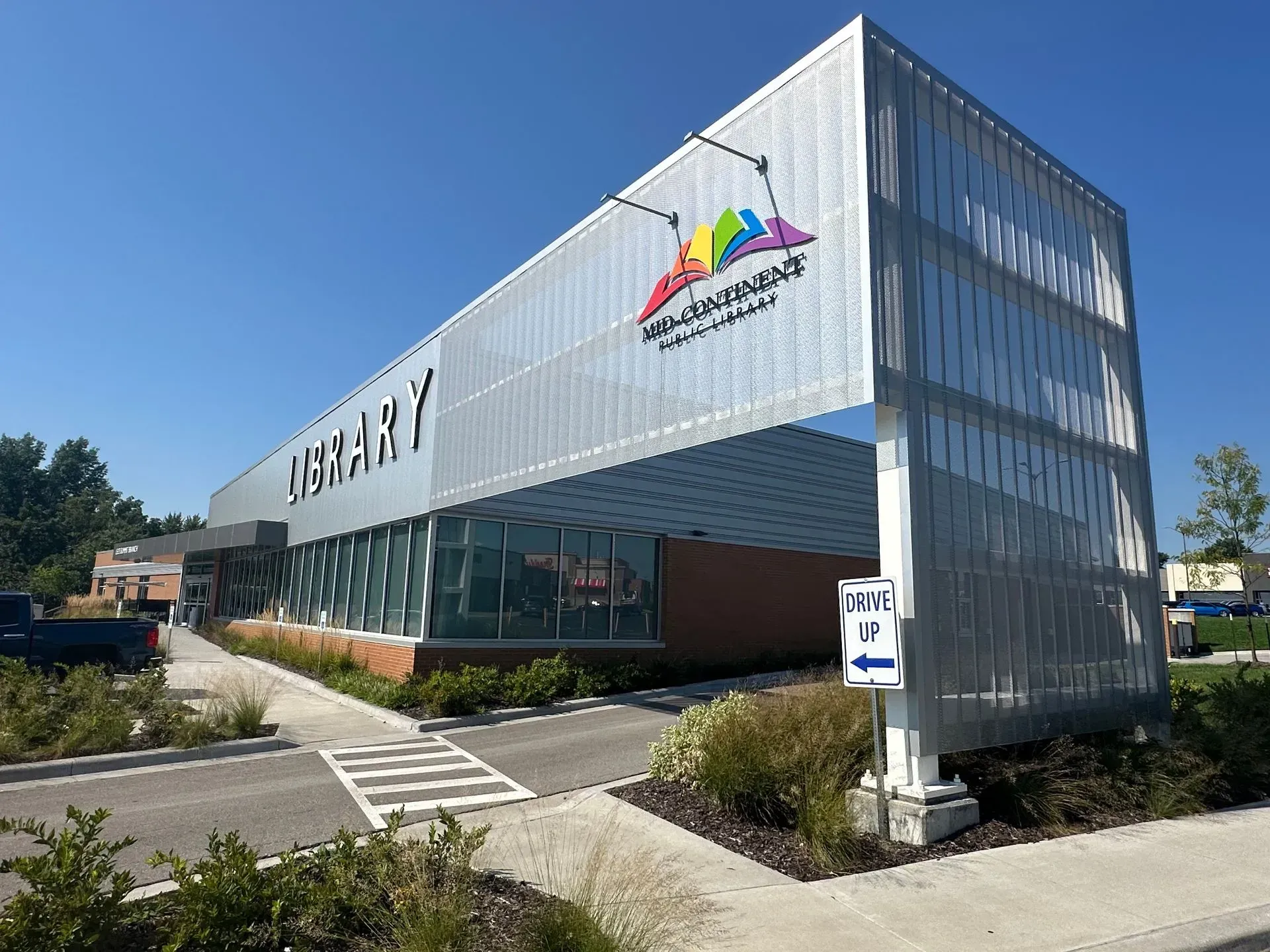 Modern library building with silver facade and colorful logo.