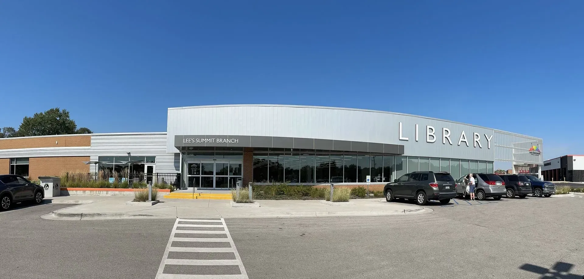 Exterior view of a library building with cars parked in front.