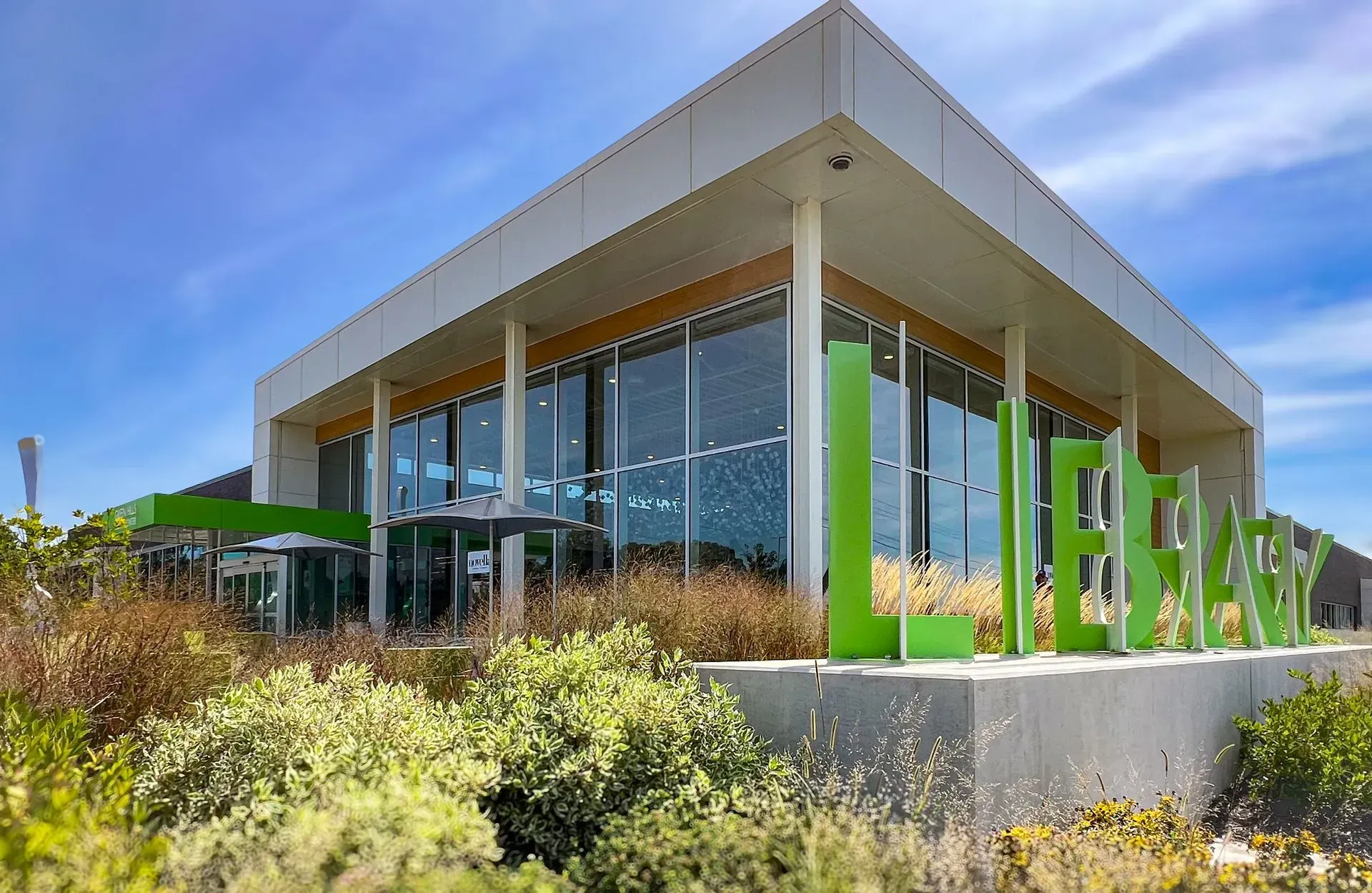 Modern library building with large windows and green.