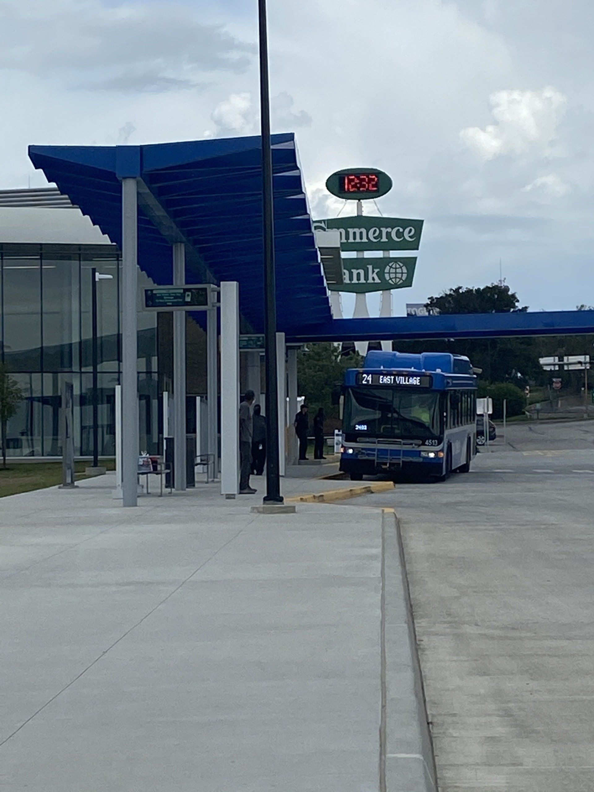 A blue bus is parked under a blue awning at a bus stop