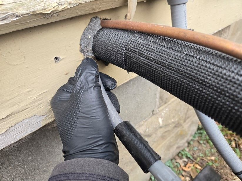 A person wearing black gloves is working on a pipe.