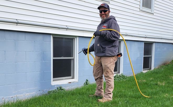 A man is spraying a house with a hose