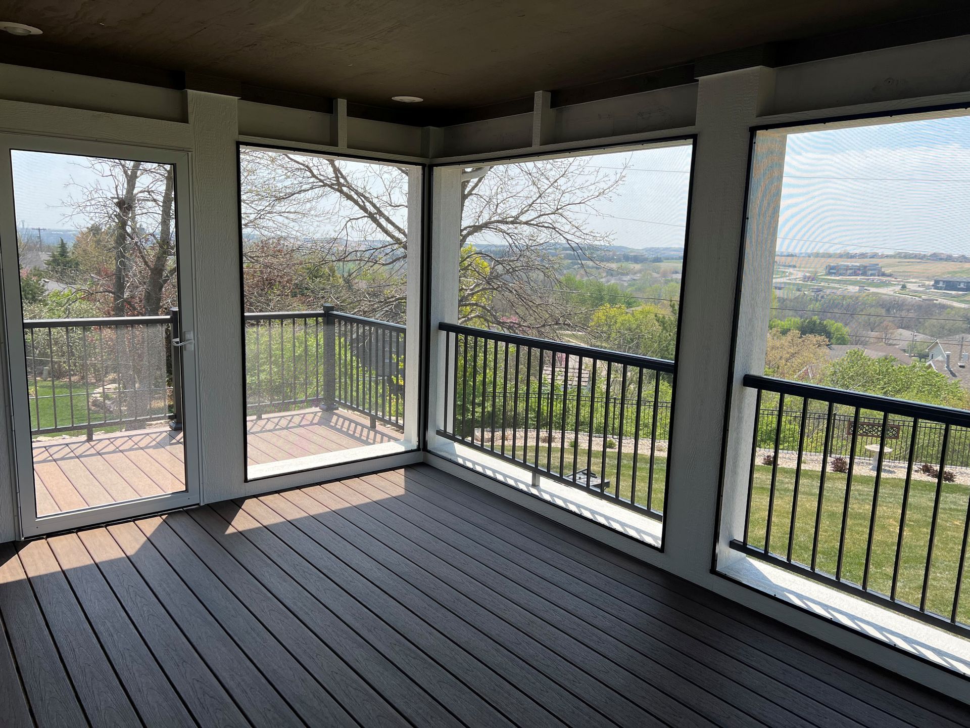 A screened in porch with a view of a hillside.