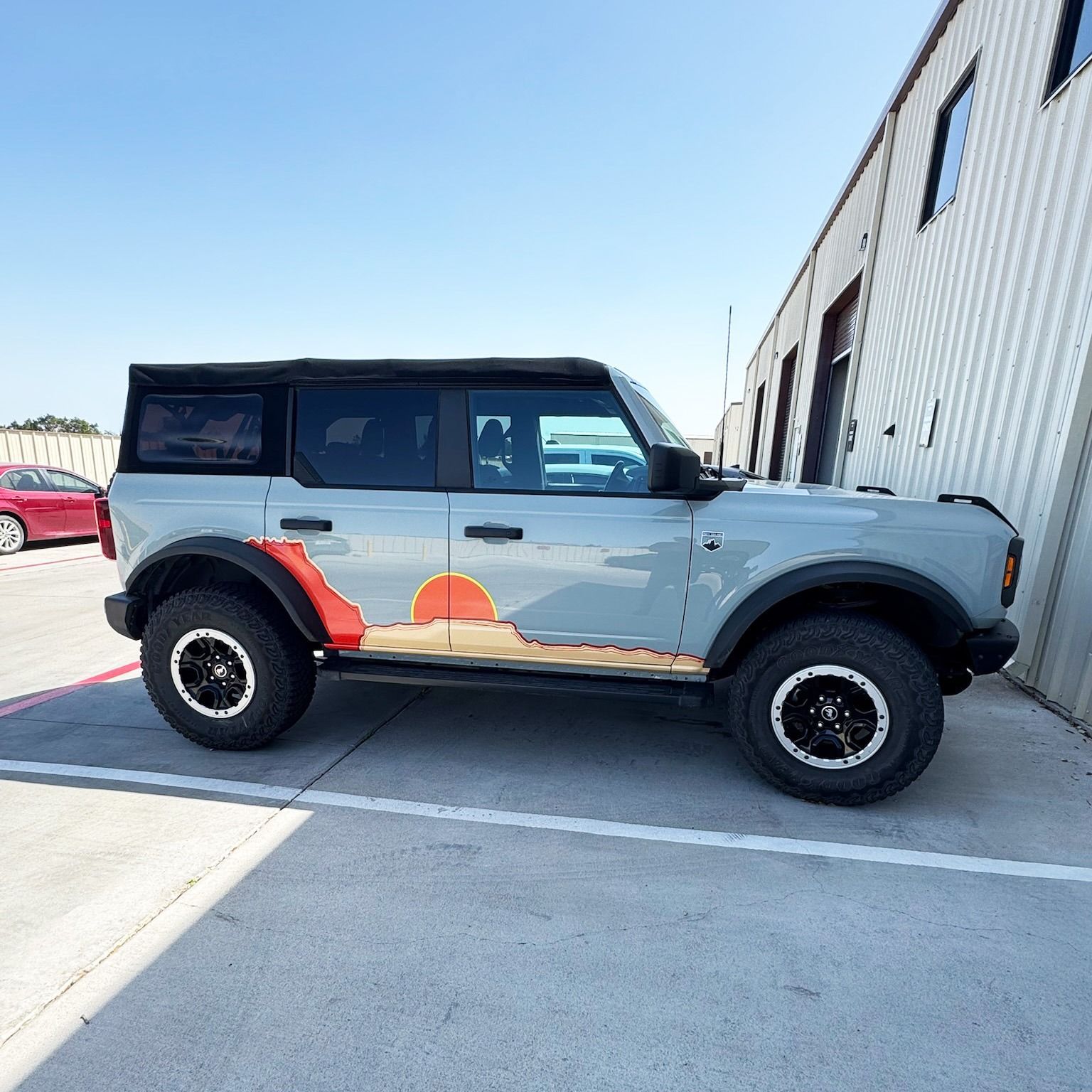 Two-tone gray off-road SUV with black roof parked beside a building on a sunny day