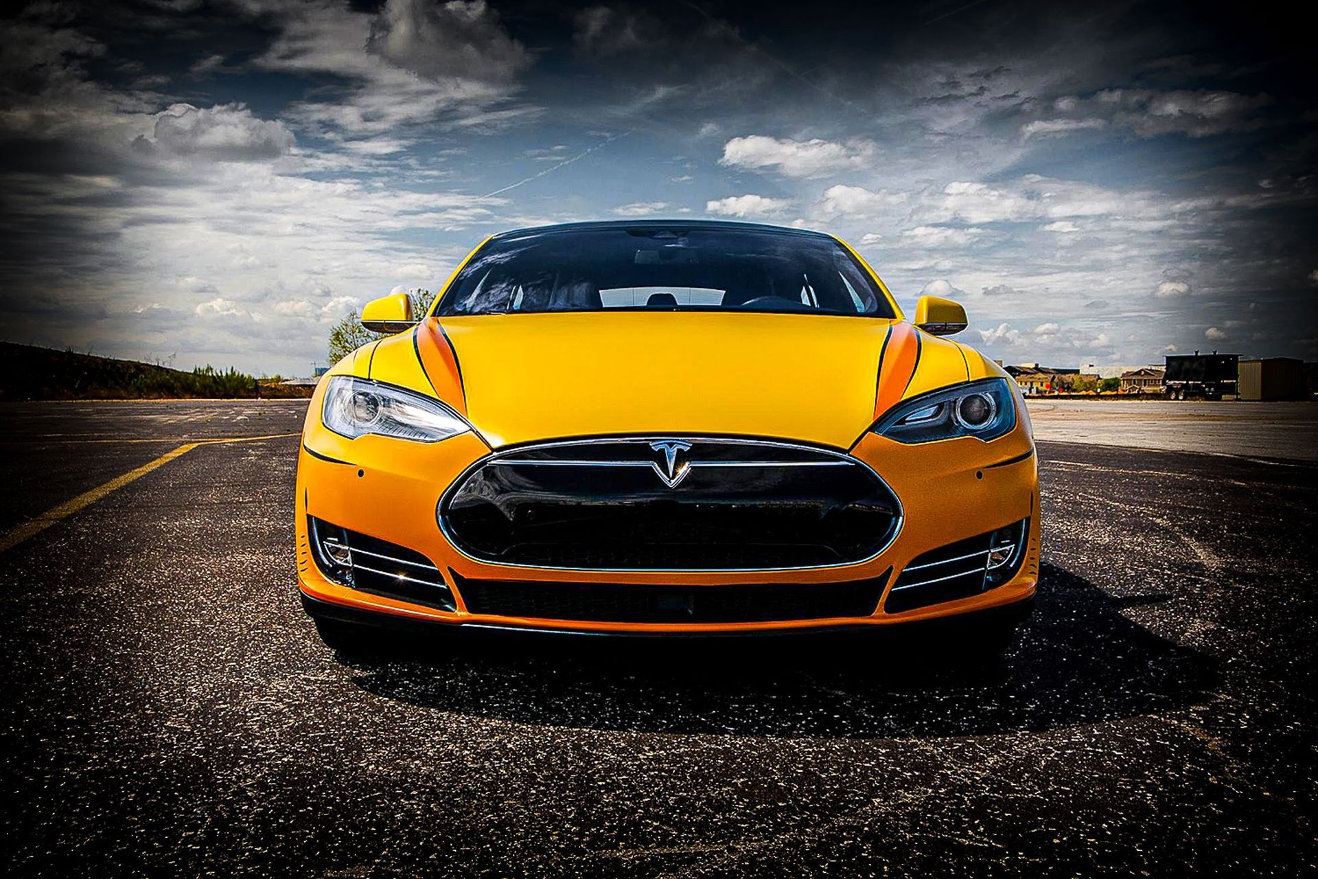 Yellow sports car on a wet road under a dramatic cloudy sky