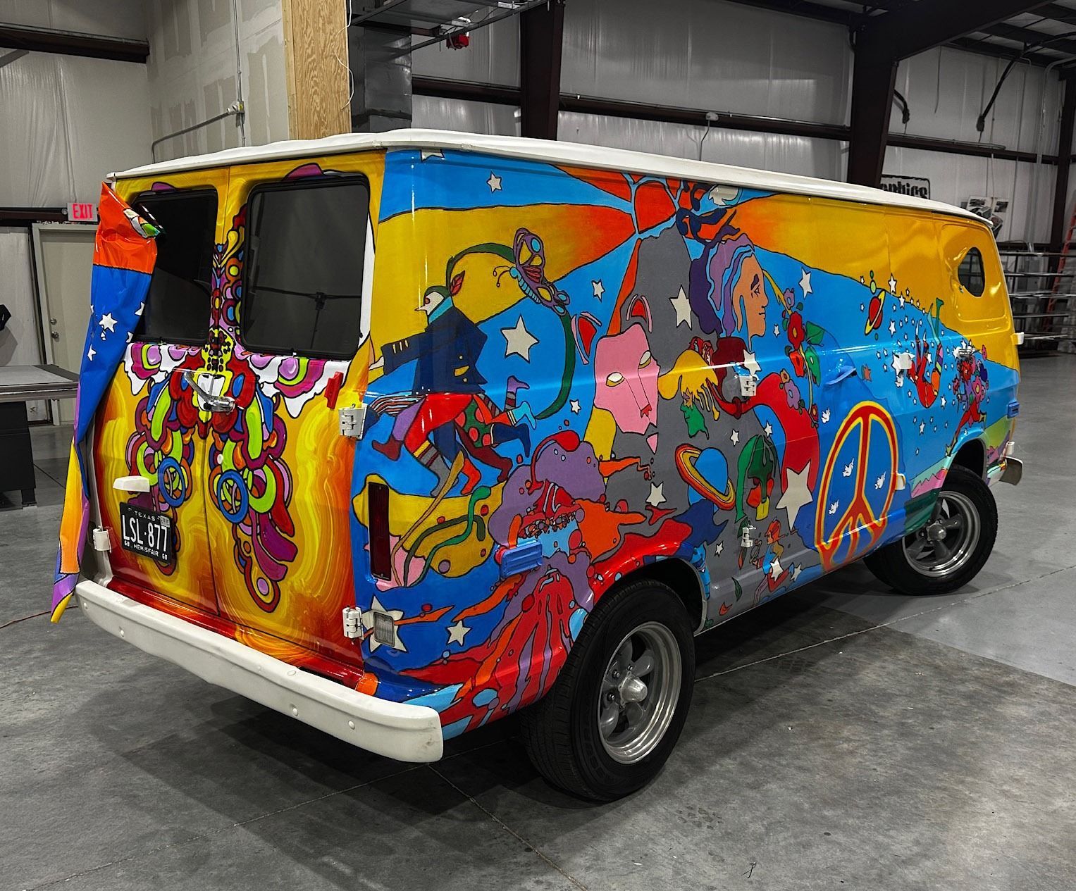 Colorful graffiti-painted van parked indoors, with yellow roof and psychedelic artwork on the sides.