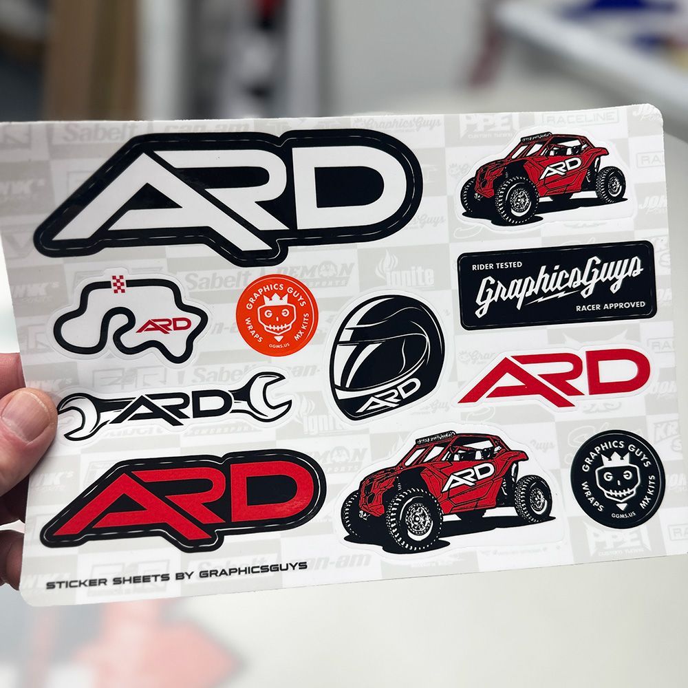Hand holding a sticker sheet with black, red, and white ARD and racing-themed graphics