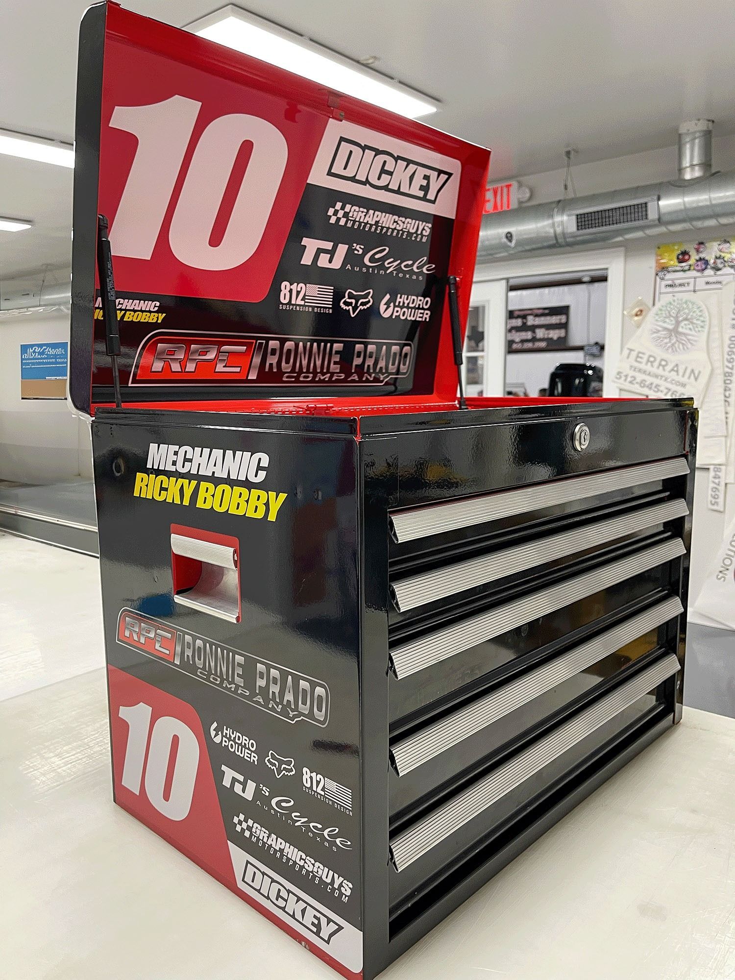 Red and black DEKALB seed display with drawers in a store aisle, featuring a large red “10” sign.