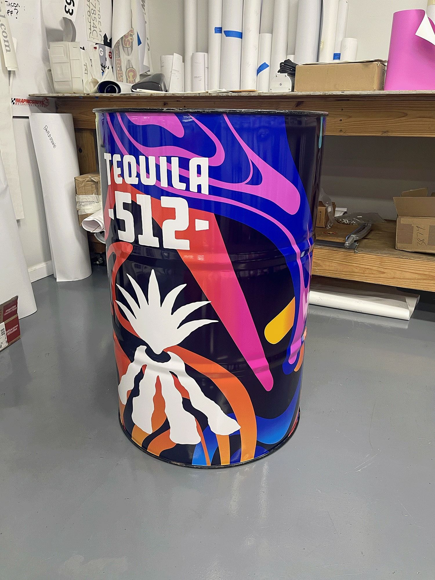 Colorful Tequila 512 barrel with neon pink, blue, and orange graphics in a workshop area