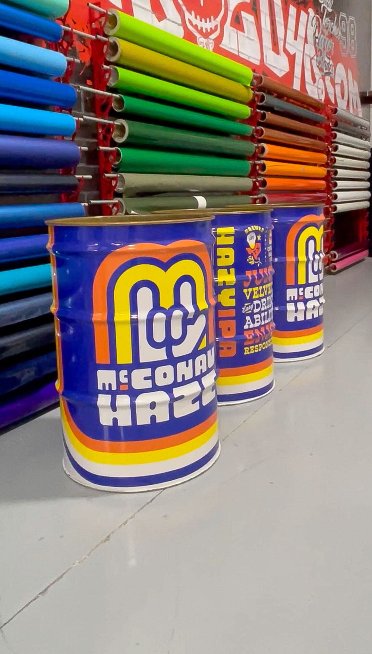 Colorful orange and purple cans on a store shelf with stacked green and red tubes behind them