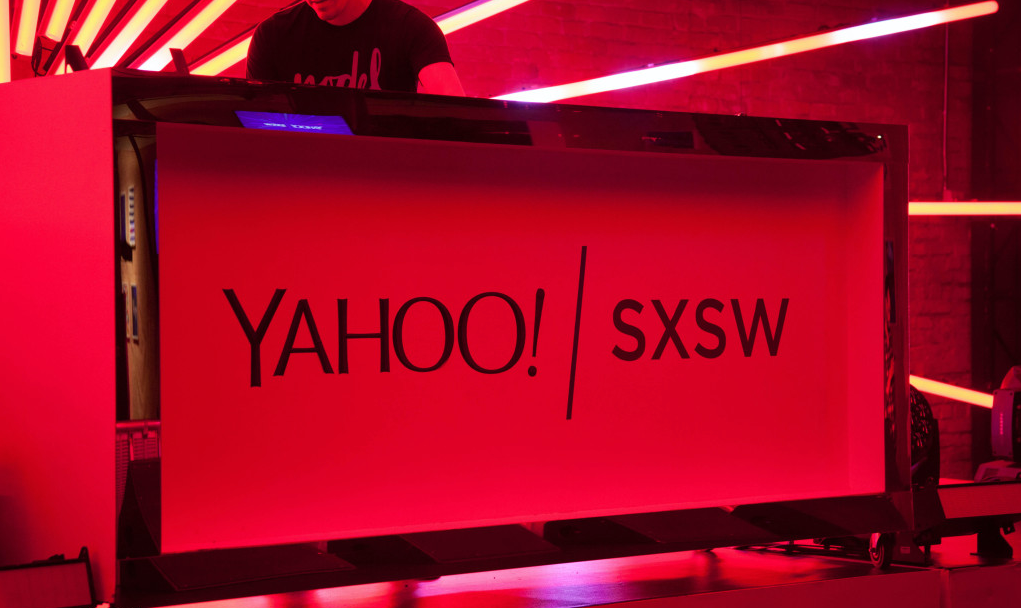 Red-lit Yahoo! SXSW sign on a stage or booth backdrop