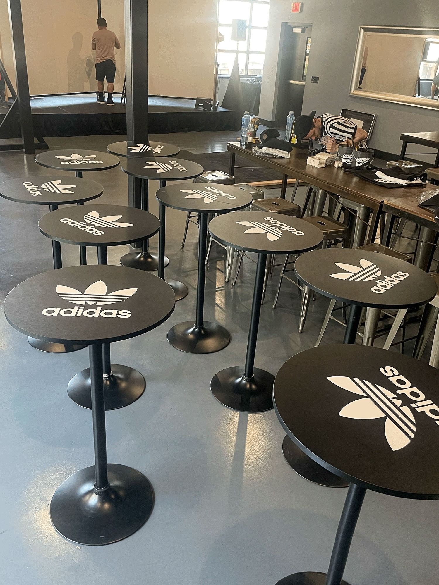 Black Adidas-branded stools arranged in a gym or training room with mirrors and equipment in the background