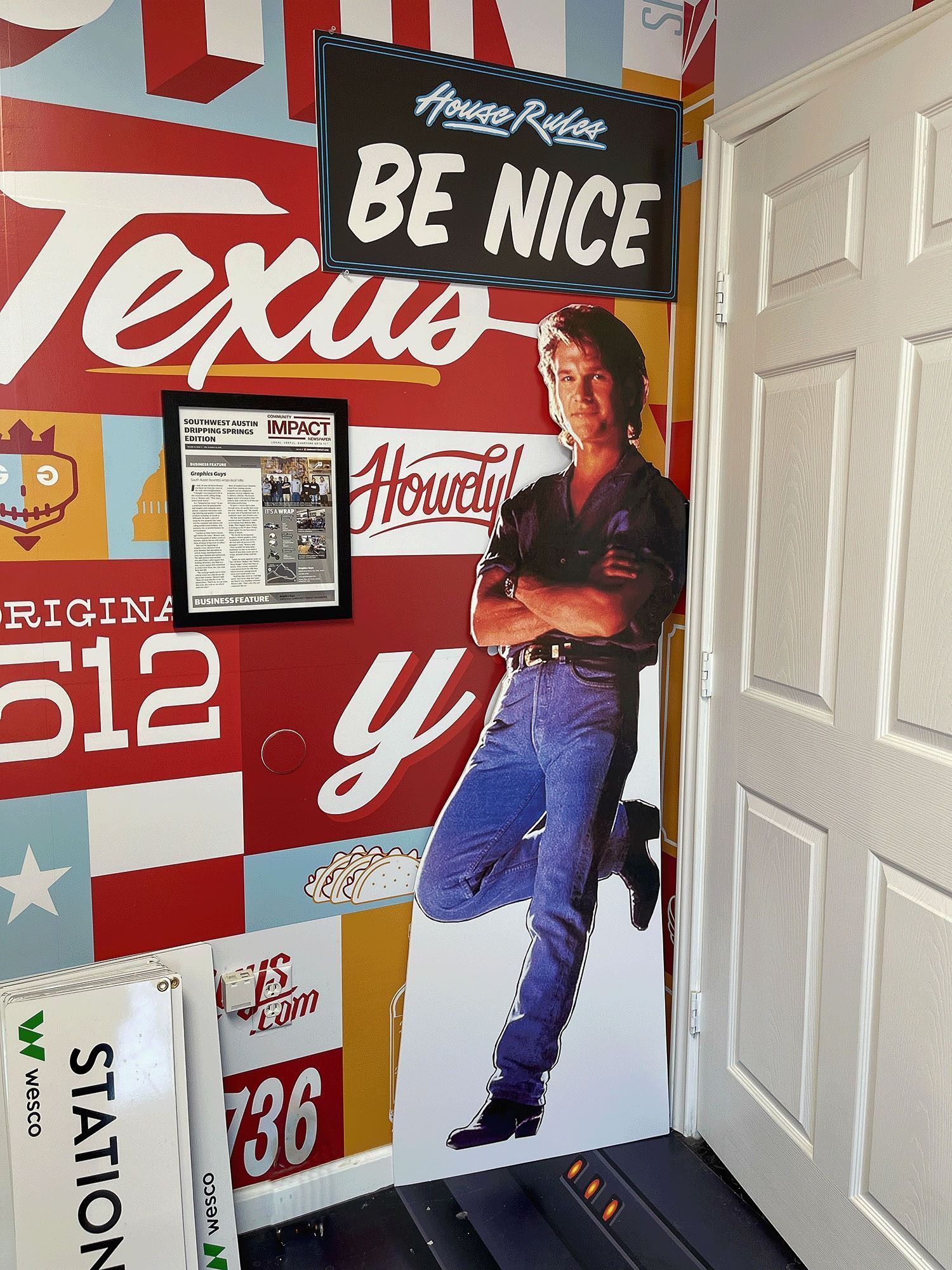 Texas-themed wall mural with red-and-white signage, “Be Nice,” and a cowboy figure beside a white door