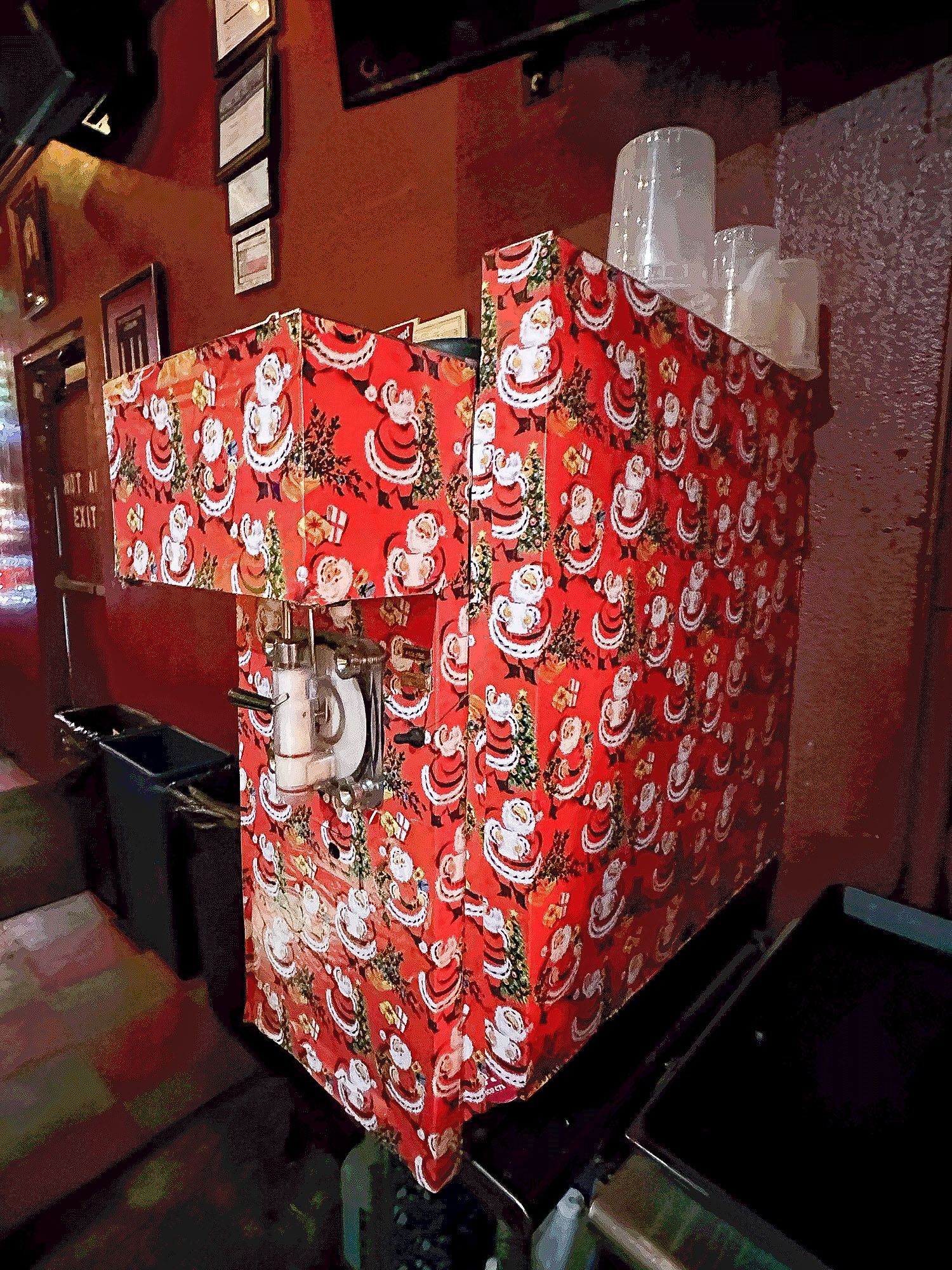 Red Santa-wrapped appliance in a dim room, with a clear cylinder and metal fixture on top