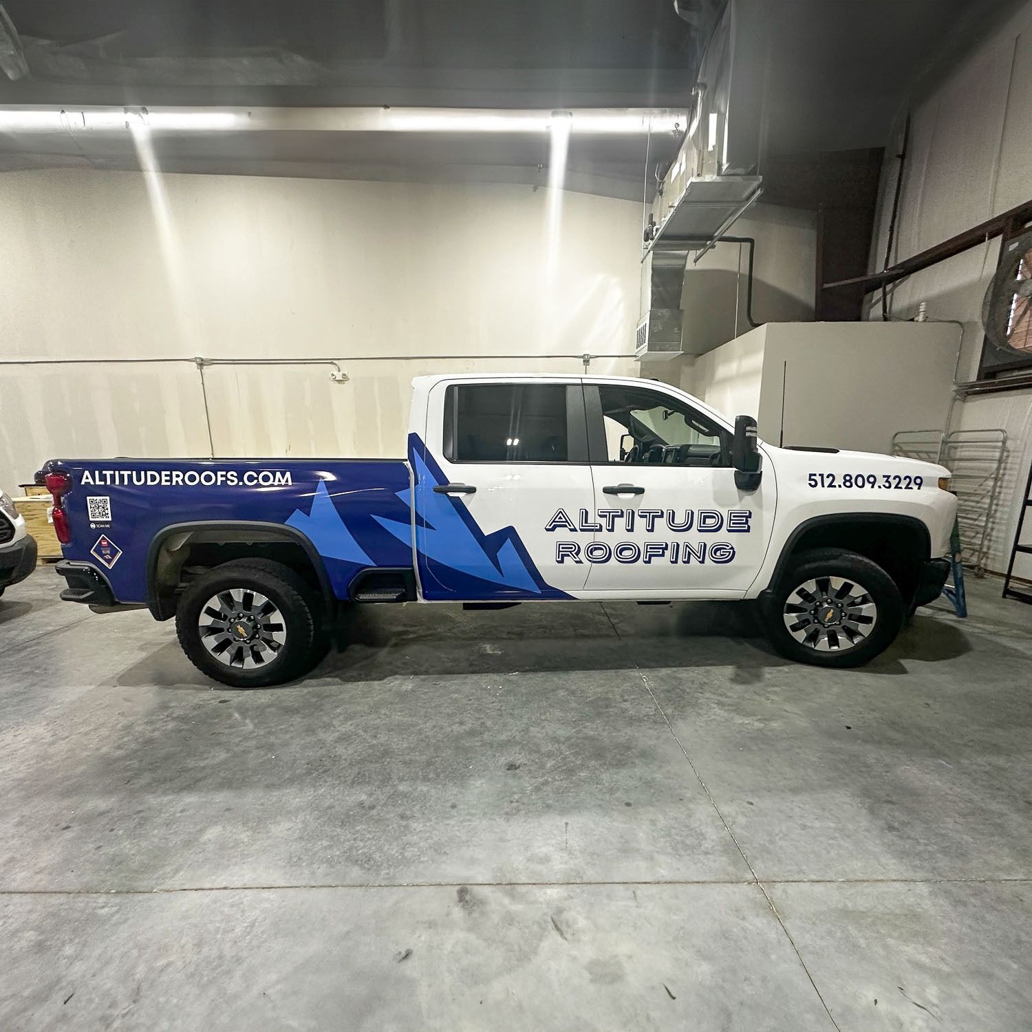 White pickup truck with blue graphics parked indoors in a garage