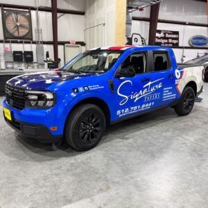 Blue Signature Electric pickup truck parked indoors at an auto facility