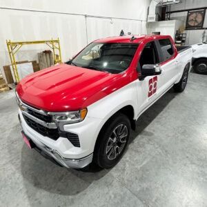 Red and white pickup truck parked indoors in a garage or showroom
