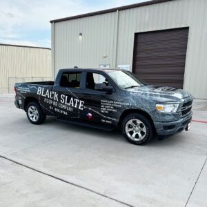 Black Slate branded black pickup truck parked outside a metal warehouse