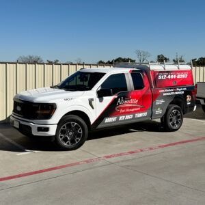 White and red service pickup truck with company graphics parked in a lot under a clear blue sky