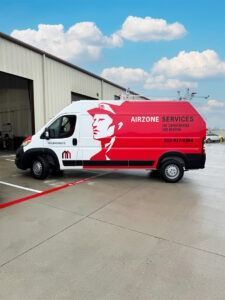 Red Airzone Services van parked outside a warehouse on a concrete lot