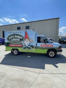 Landscape truck with “Just Right Lawns” logo and gnome, parked outside a warehouse