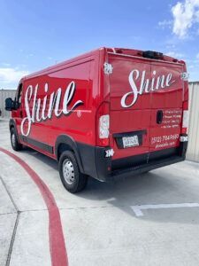 Red Shine van parked on a curved driveway under a blue sky
