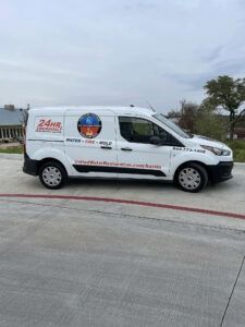White utility van with company logos parked on a concrete lot under a cloudy sky