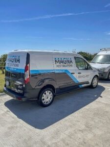 Silver MAGNA Pest Control van parked outdoors under a clear blue sky.