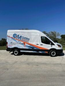 White delivery van with blue and orange graphics parked on a sunny lot