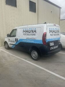 Maguia Pest Solutions van parked beside a beige building in a concrete lot