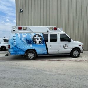 Blue-and-white ambulance van parked outside a building with unit 12 sign
