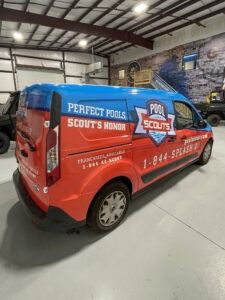 Red and blue pool service van with “Perfect Pools” branding parked in a garage