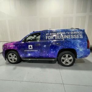 Purple Atmosphere business van with “Streaming TV Service for Businesses” signage in a white indoor space