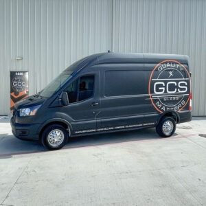 Dark blue GCS-branded cargo van parked outside a corrugated metal building