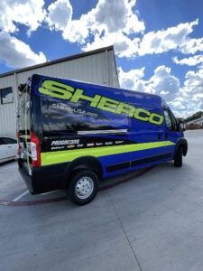 Blue Sherco-branded van parked outdoors under a cloudy sky