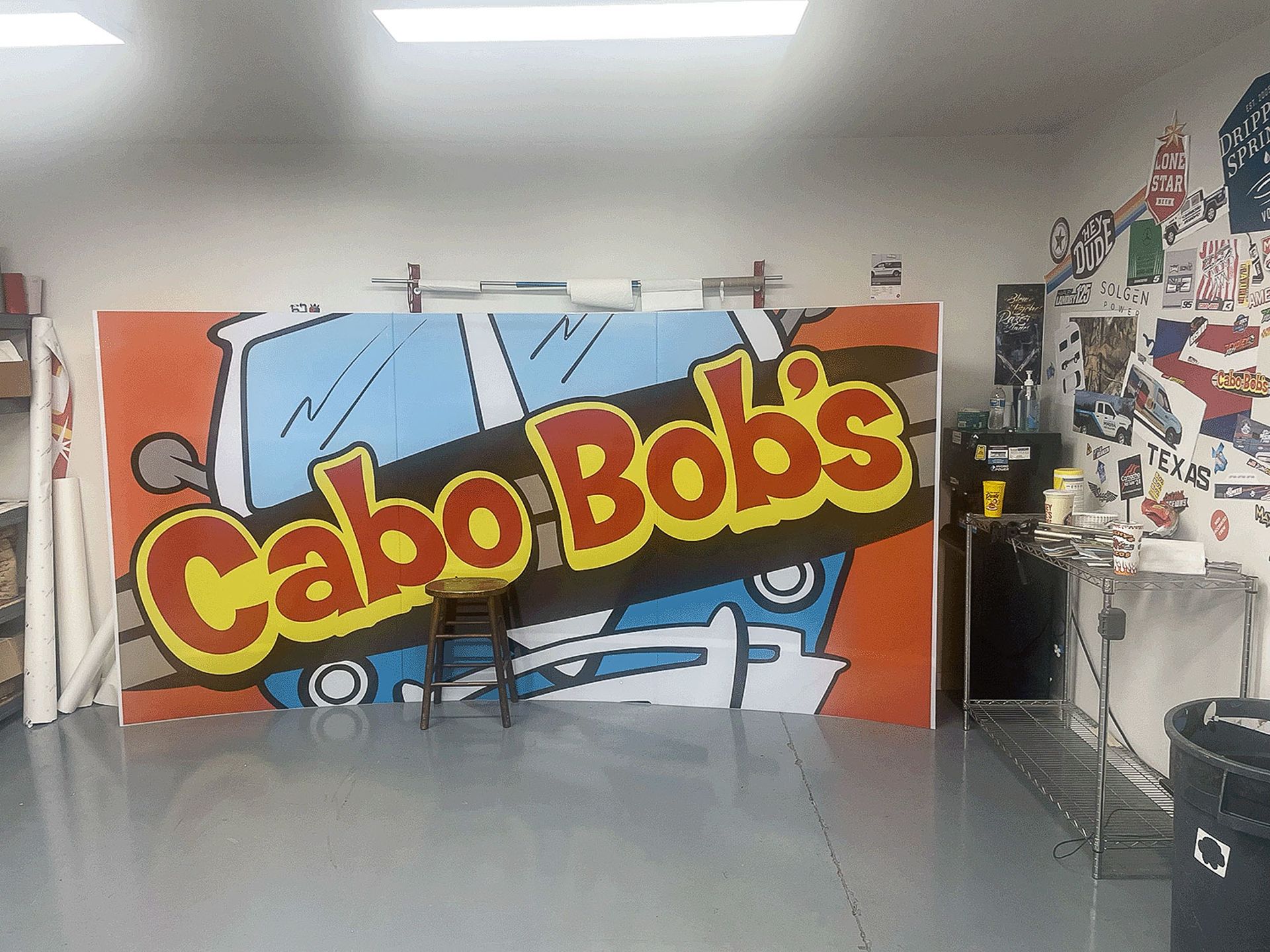 Colorful Cabo Bob’s mural on a wall in a room with art supplies and posters nearby