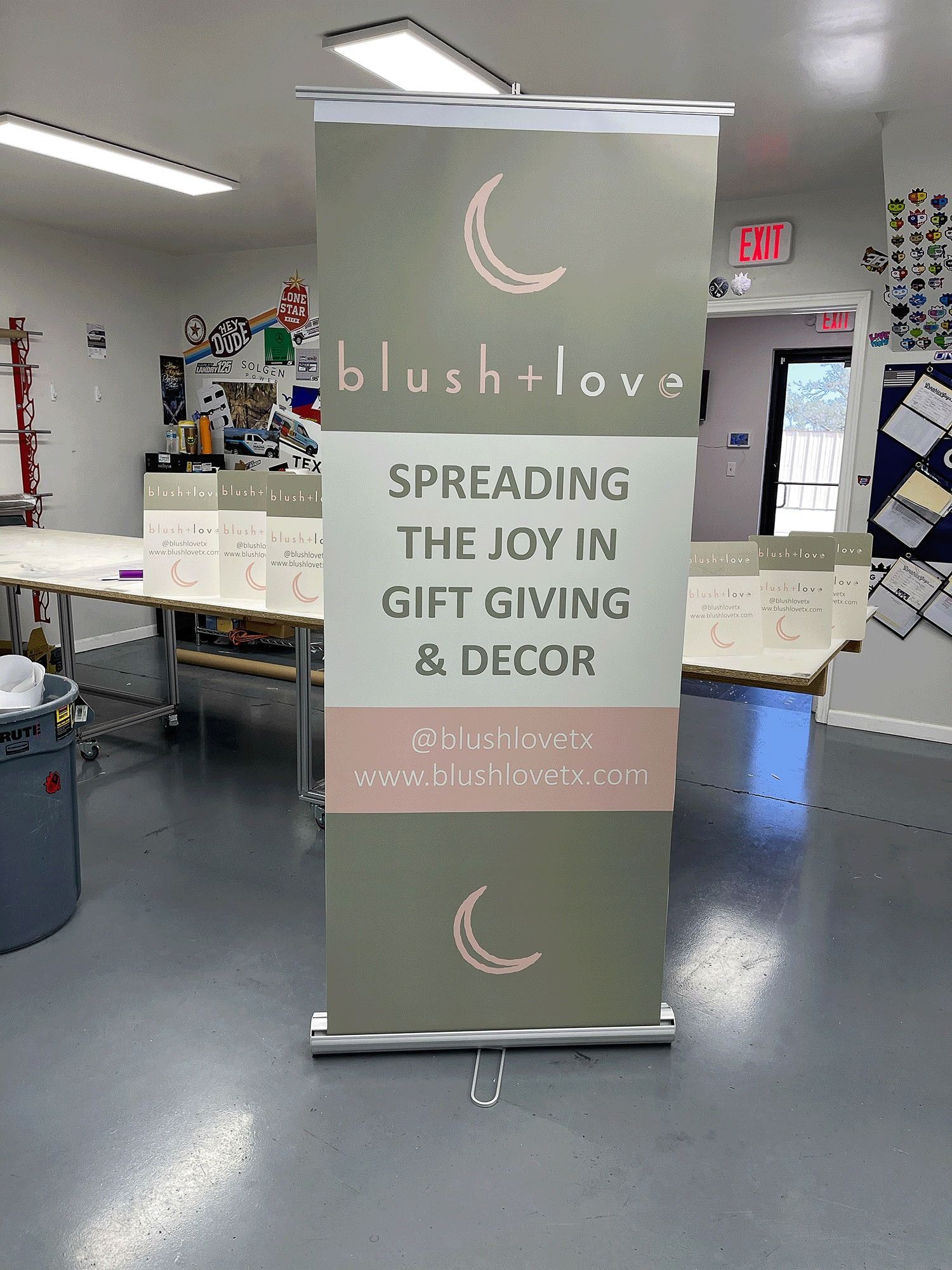 Tall gray banner in a gift shop reads “blush+love” and “Spreading the joy in gift giving & decor.”
