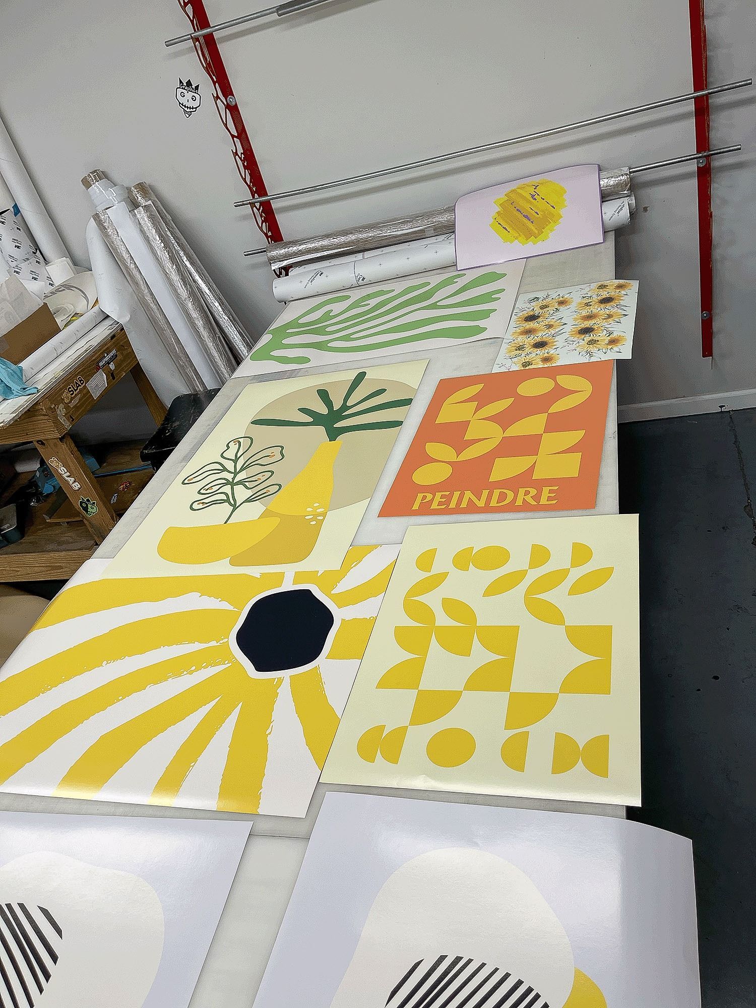 Colorful abstract floral prints laid out on a table in a studio or workshop