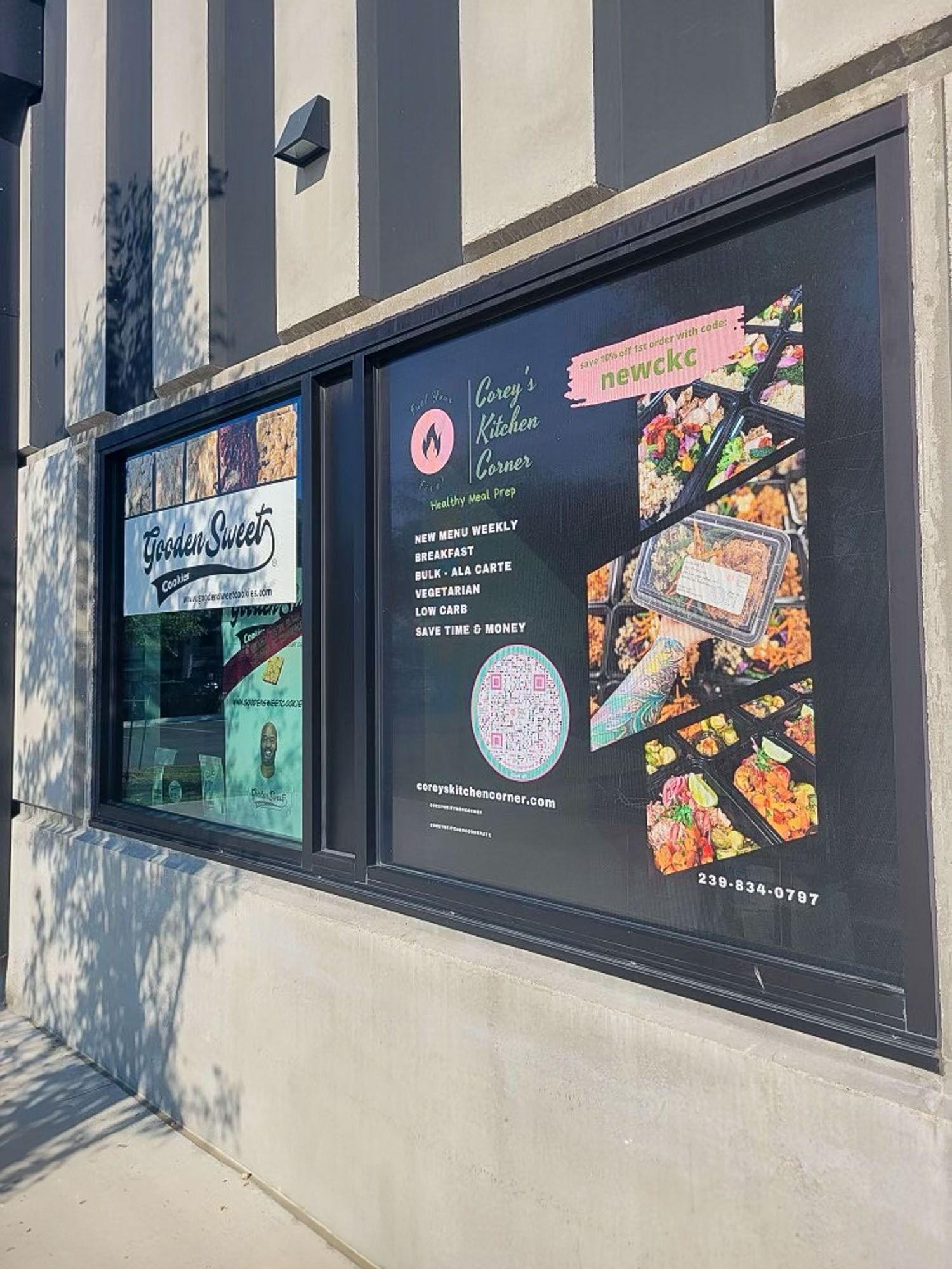 Storefront window with colorful food menu posters and reflections on a sunny sidewalk
