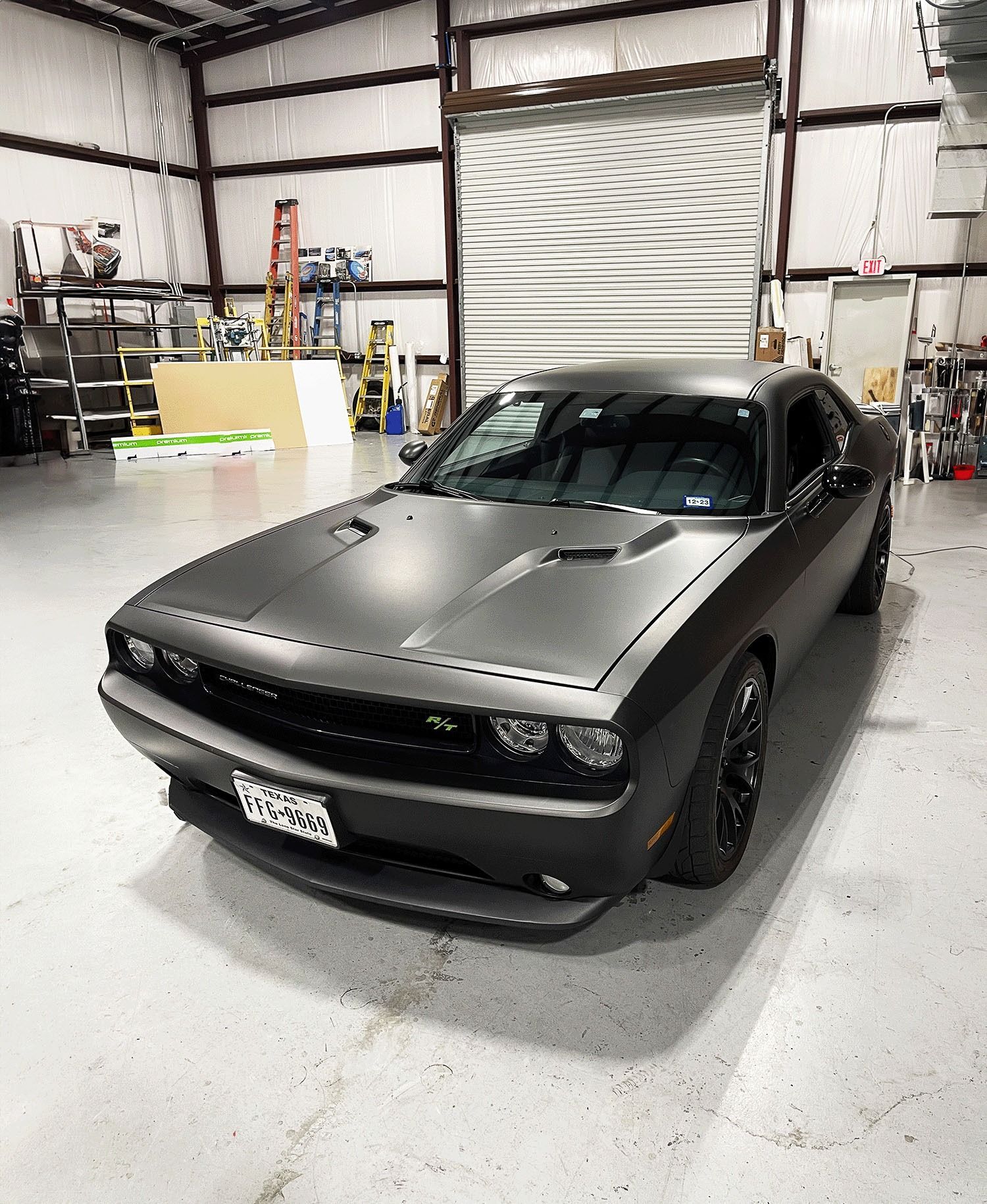 Matte black sports coupe parked in a warehouse garage.