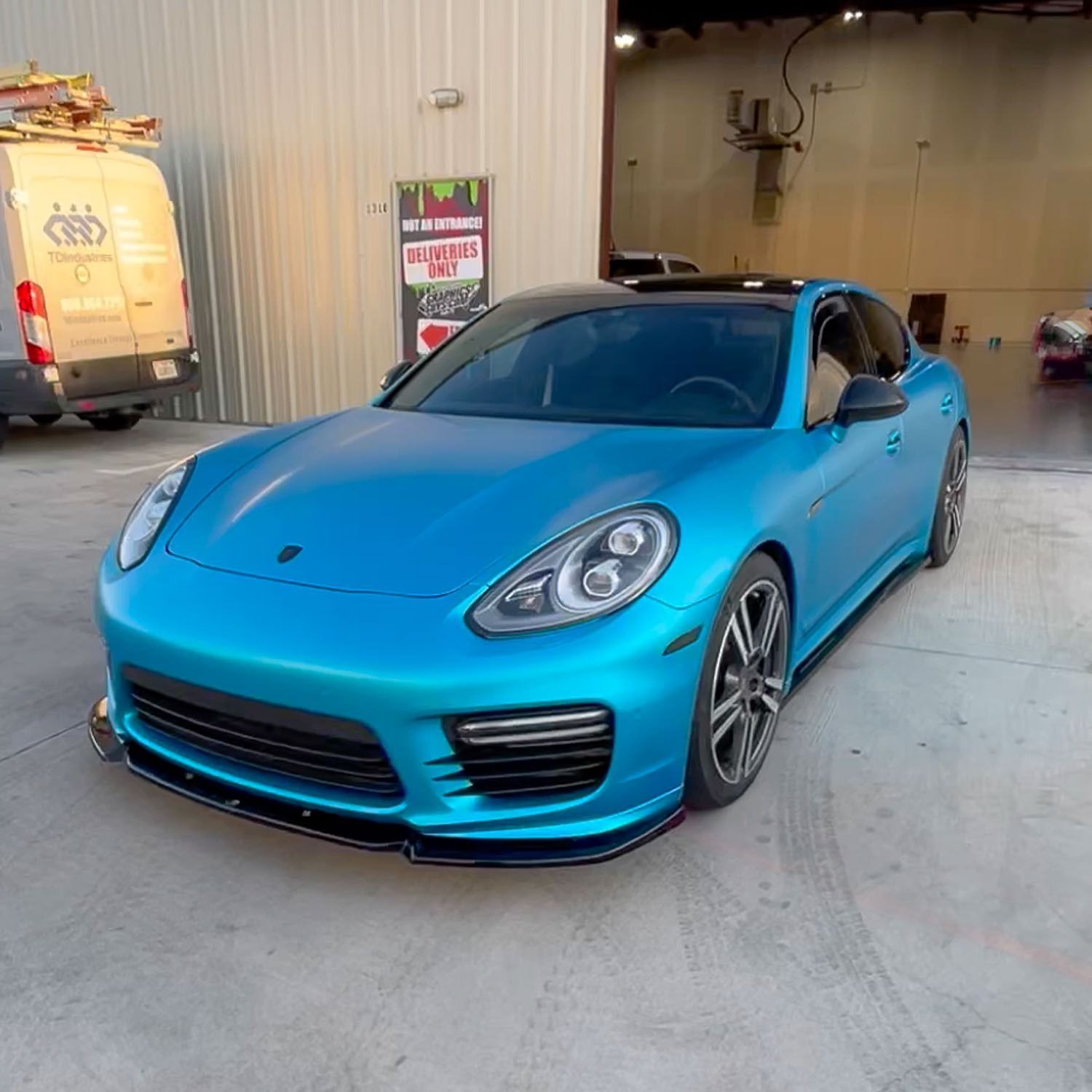 Blue sports car parked outside a garage with a custom low front bumper