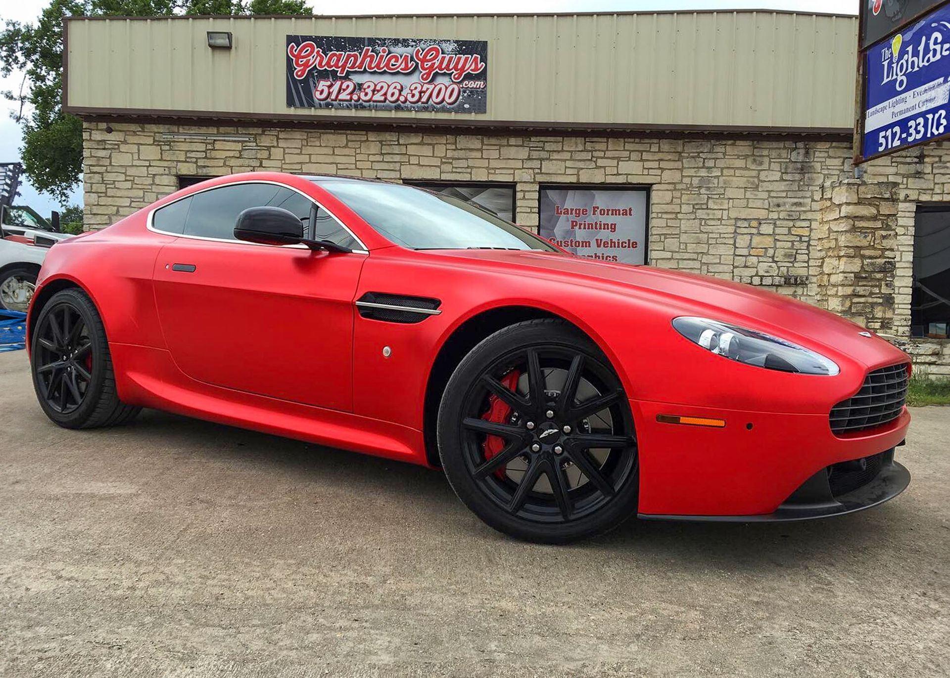 Red sports car parked outside a brick building with a sign above the entrance