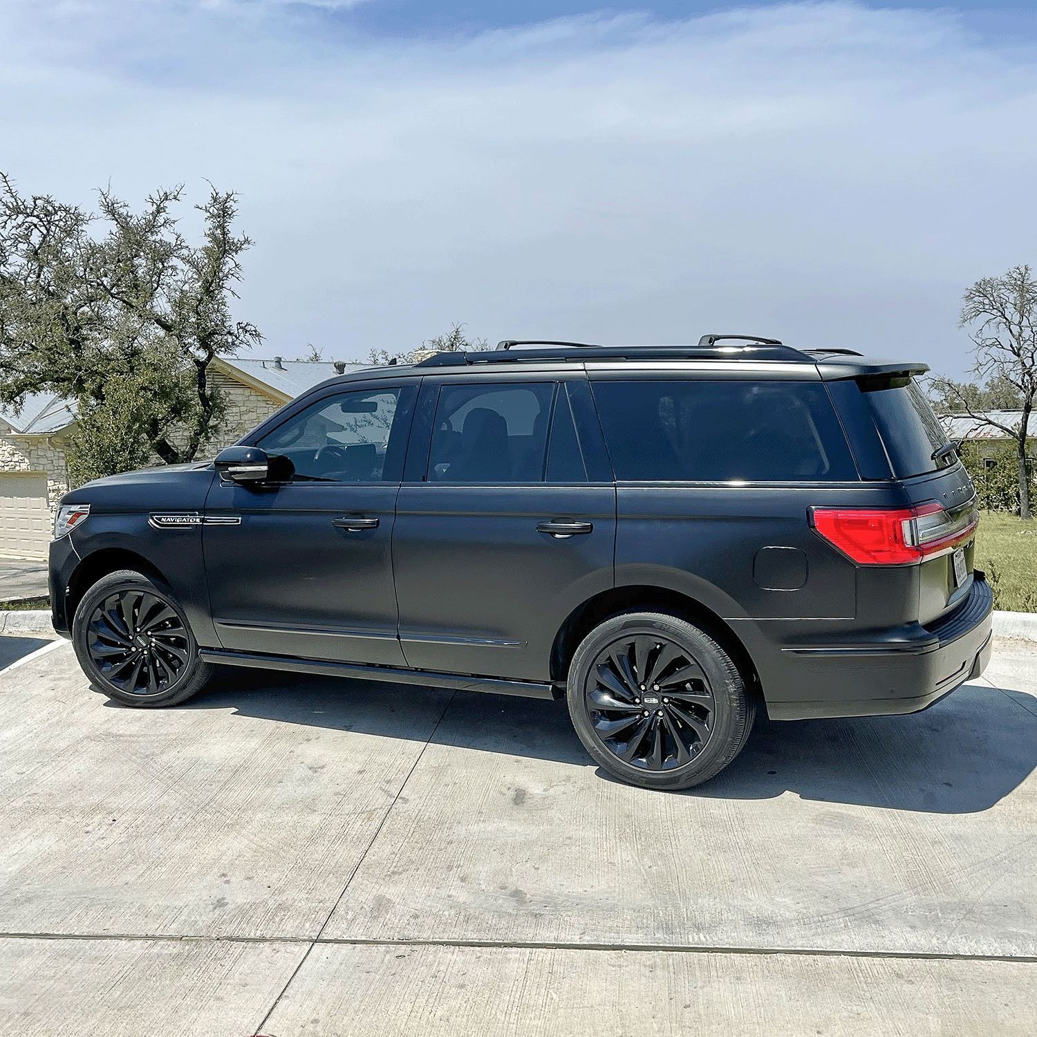 Black SUV parked on a concrete lot under a blue sky, side view