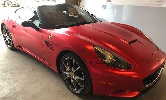 Red Ferrari sports car parked in a garage, viewed from the front-left side