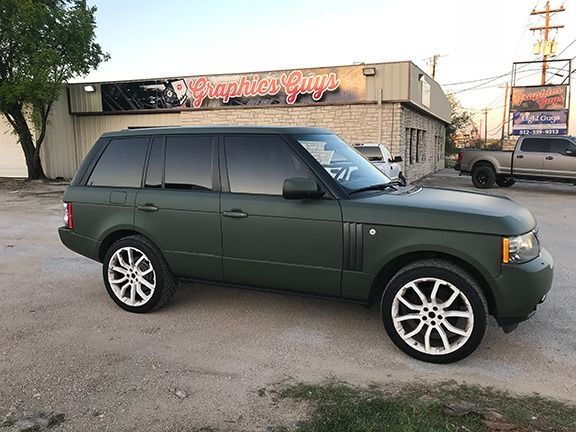 Dark green SUV parked outside a storefront on a street.