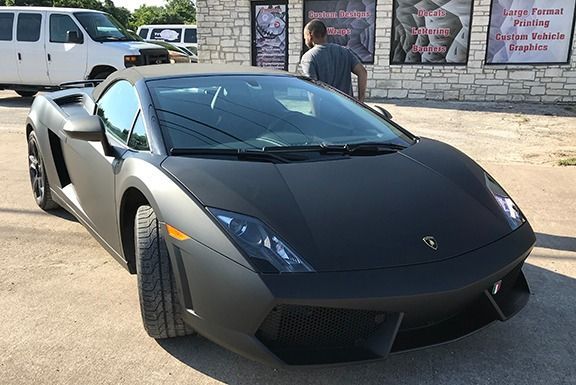 Black Lamborghini sports car parked outside a storefront