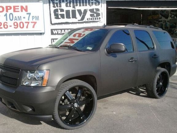 Matte gray SUV with black rims parked outside a shop